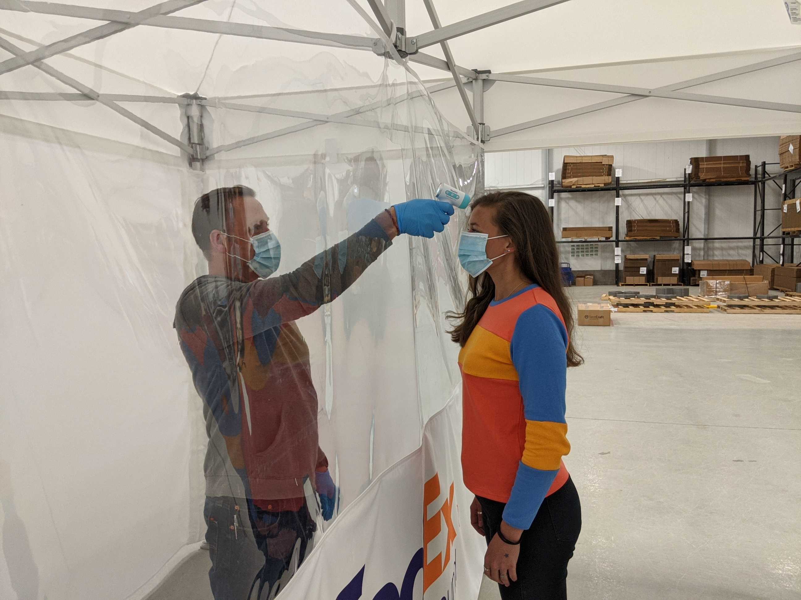 employee temperature screening happening inside of a popuptent with vinyl seperator