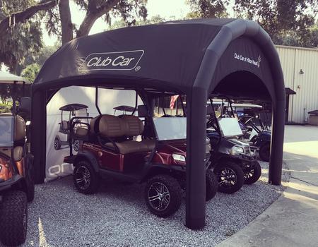 A black Nitrox AIRFRAME inflatable tent used to protect two Club Car vehicles.